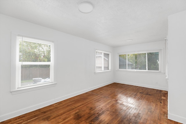 empty room featuring wood-type flooring, a textured ceiling, and baseboards