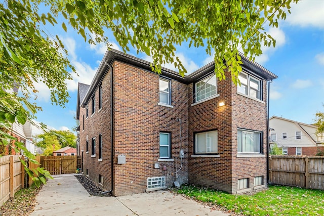 back of property featuring a patio, brick siding, and a fenced backyard