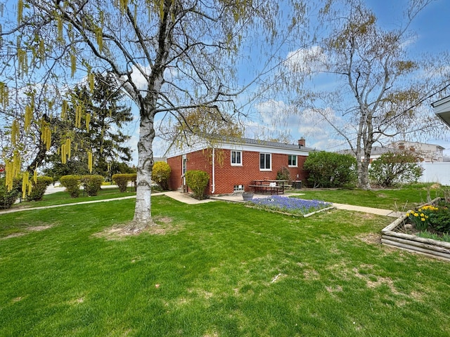 back of house with a patio, brick siding, a chimney, and a yard