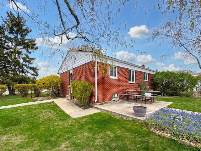 rear view of property featuring a patio, fence, a yard, and brick siding