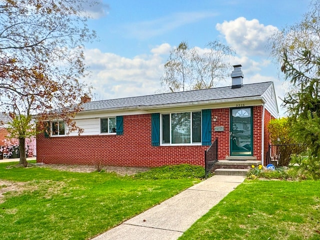 view of front of home with a front yard, brick siding, and a chimney