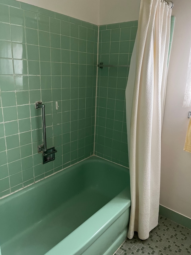 bathroom featuring baseboards and shower / bathtub combination with curtain