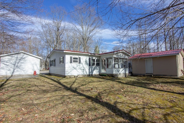 view of front facade featuring a front lawn, a sunroom, crawl space, entry steps, and an outbuilding