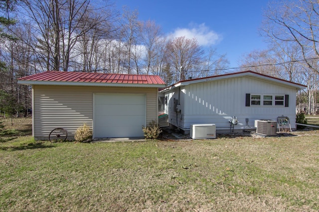 exterior space featuring a lawn, cooling unit, metal roof, and an outdoor structure