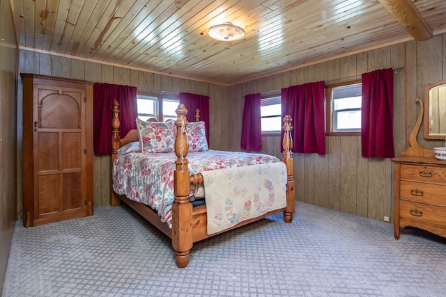 bedroom with carpet flooring, wooden walls, and multiple windows