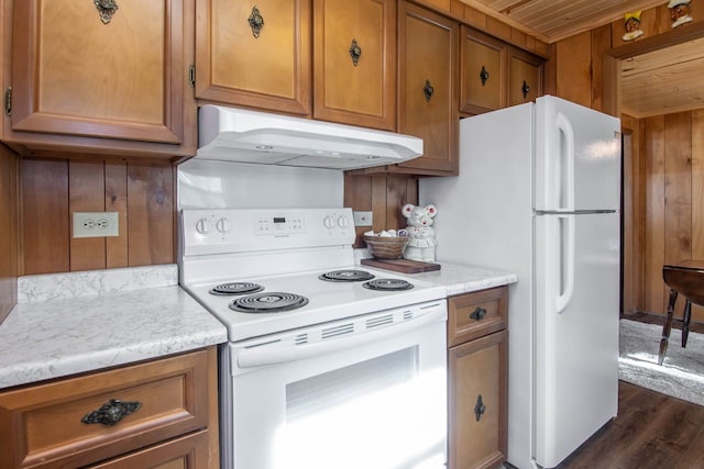 kitchen with white appliances, dark wood finished floors, brown cabinetry, wooden ceiling, and under cabinet range hood