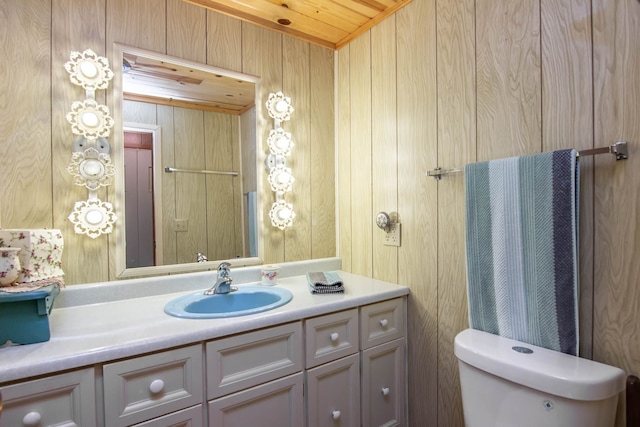 bathroom featuring wooden walls, vanity, wood ceiling, and toilet