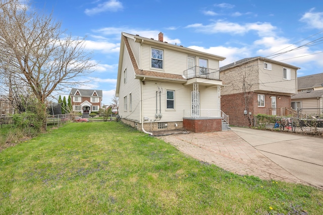 back of property with a patio area, a balcony, a fenced backyard, a lawn, and a chimney