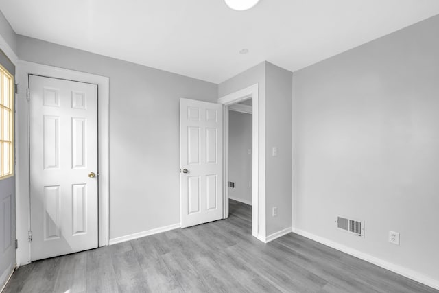 unfurnished bedroom featuring baseboards, visible vents, and wood finished floors