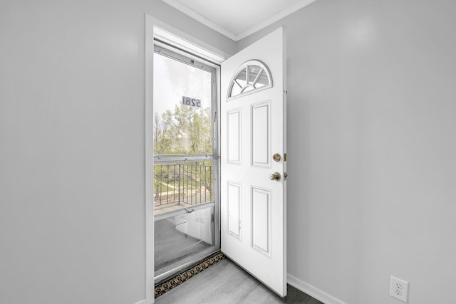 doorway to outside featuring baseboards and crown molding