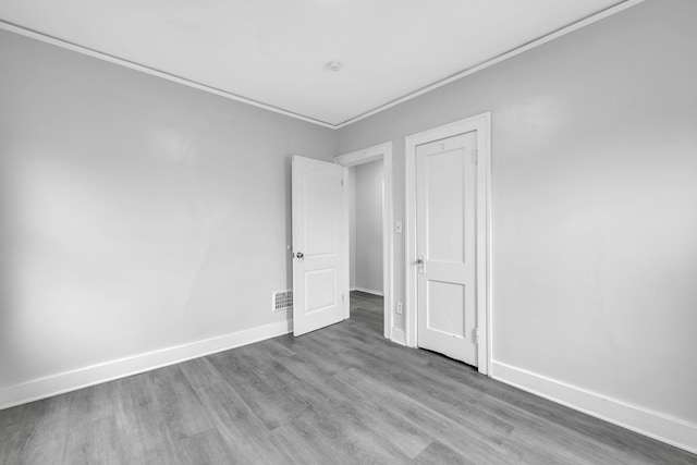 empty room featuring visible vents, wood finished floors, ornamental molding, and baseboards