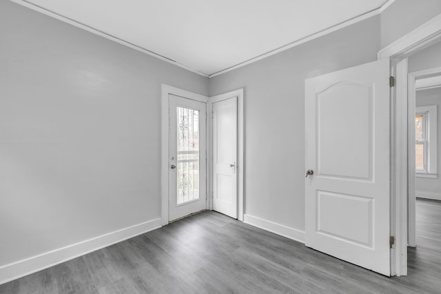 spare room with wood finished floors, crown molding, and baseboards