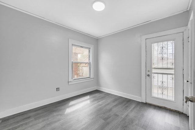 spare room with baseboards, ornamental molding, and wood finished floors