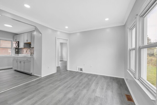unfurnished living room with visible vents, light wood-style flooring, and baseboards
