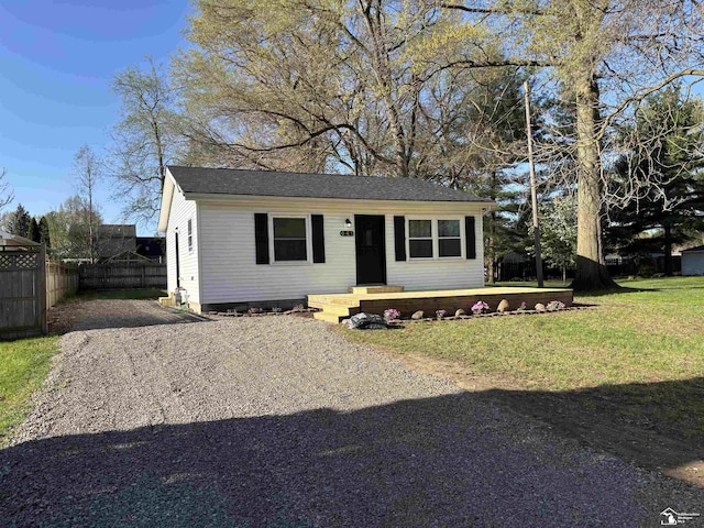 view of front of property with fence, a front yard, and driveway