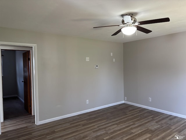 spare room with baseboards, ceiling fan, and dark wood-type flooring