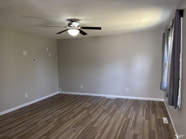 spare room featuring ceiling fan, dark wood finished floors, and baseboards