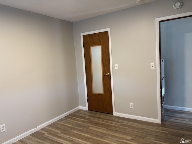 empty room with dark wood finished floors and baseboards