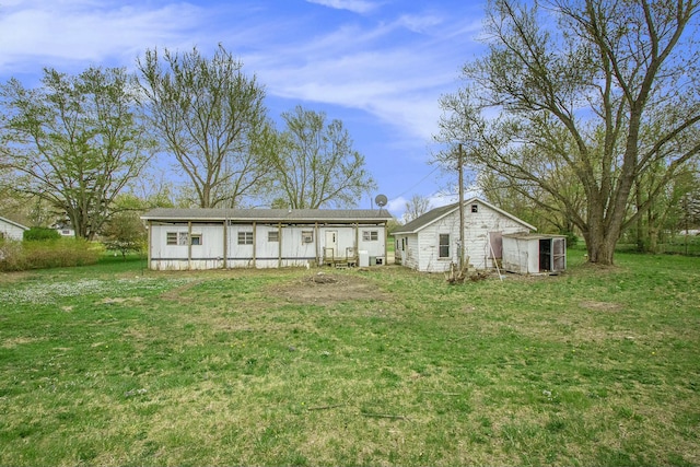 rear view of property with an outdoor structure and a yard