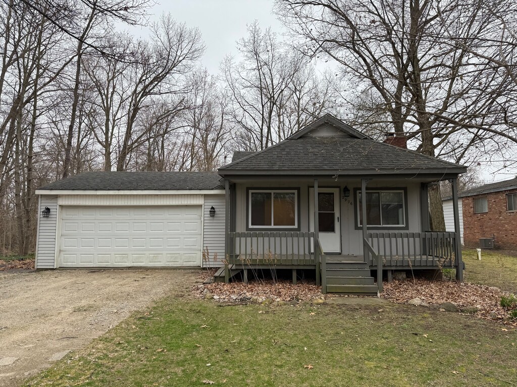view of front of house featuring a chimney, a porch, a shingled roof, a garage, and driveway
