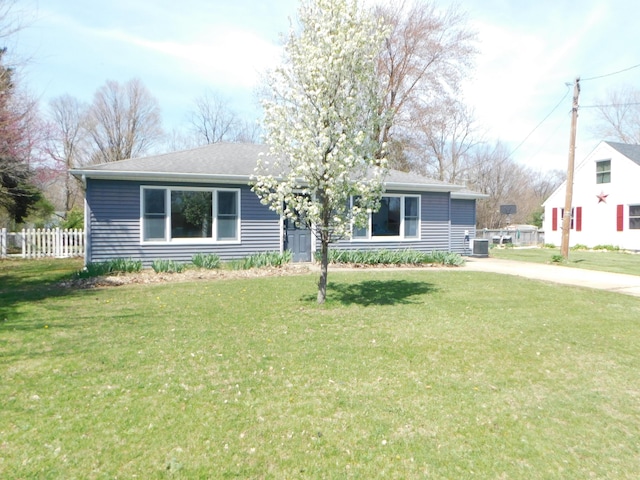 ranch-style home featuring fence, central AC, and a front lawn