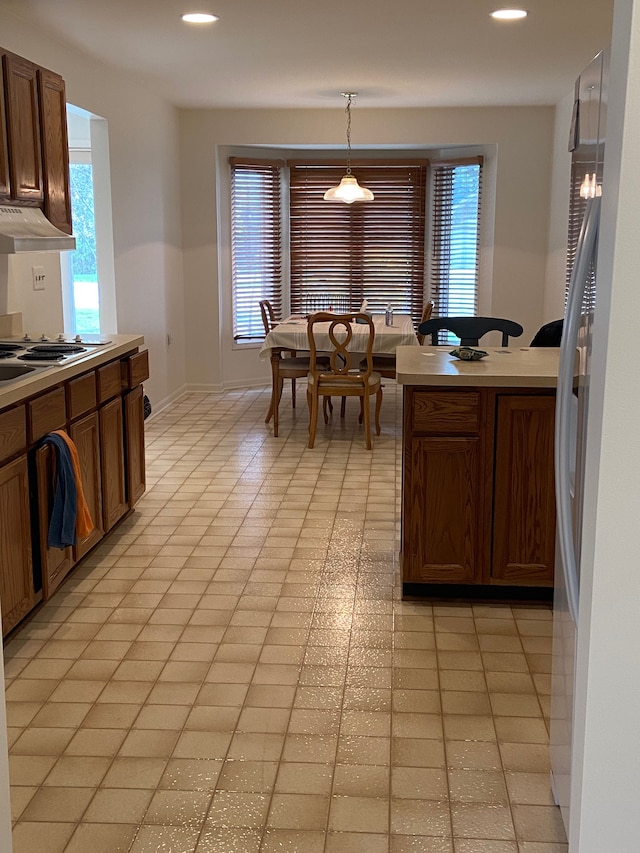 kitchen featuring light countertops, baseboards, under cabinet range hood, recessed lighting, and hanging light fixtures