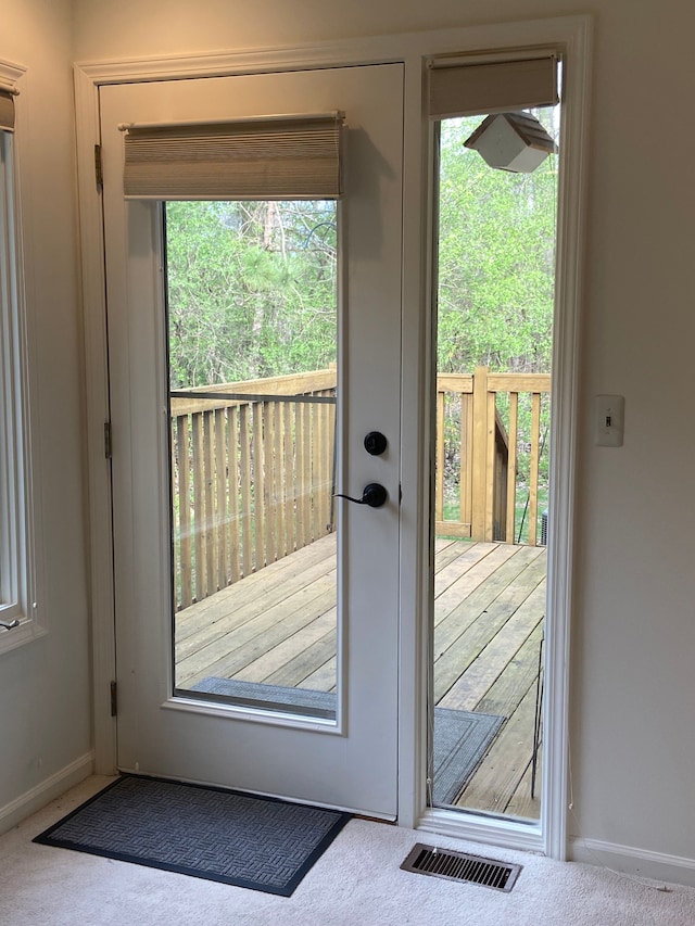 doorway to outside featuring baseboards, visible vents, a wealth of natural light, and carpet