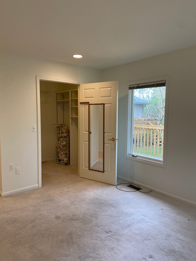 unfurnished bedroom with baseboards, a spacious closet, a closet, and carpet