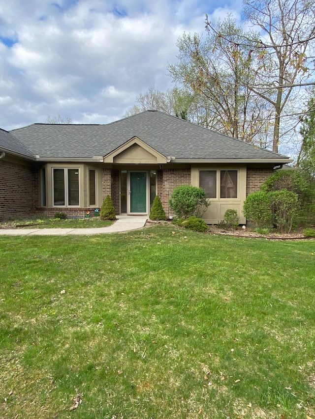 single story home featuring a front lawn, roof with shingles, and brick siding