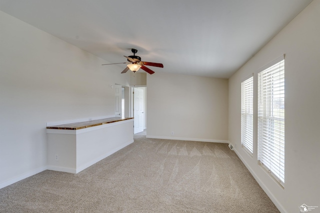 unfurnished room with a ceiling fan, baseboards, light carpet, and plenty of natural light