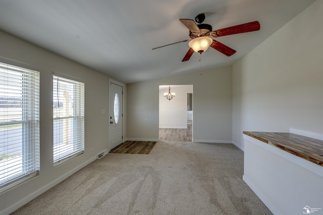 unfurnished living room featuring baseboards, visible vents, ceiling fan with notable chandelier, and carpet flooring