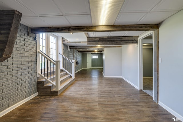 interior space featuring dark wood-type flooring, brick wall, stairs, and baseboards