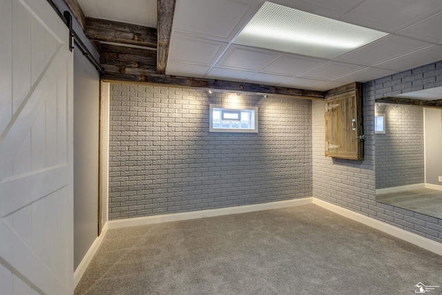 below grade area with baseboards, a barn door, and carpet