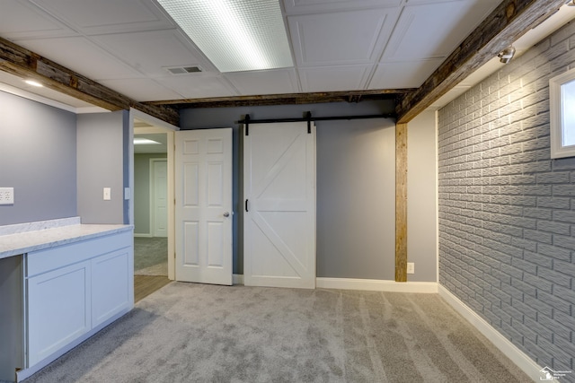 below grade area featuring visible vents, a barn door, and light colored carpet