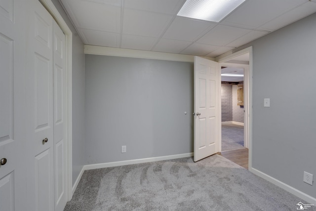 interior space with a drop ceiling, baseboards, and carpet floors