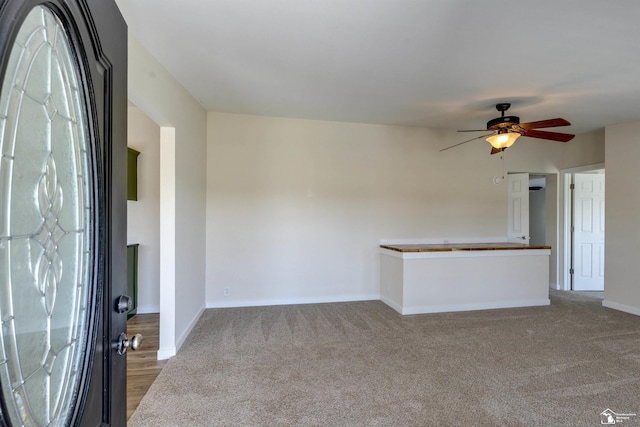 unfurnished living room with baseboards, a ceiling fan, and carpet