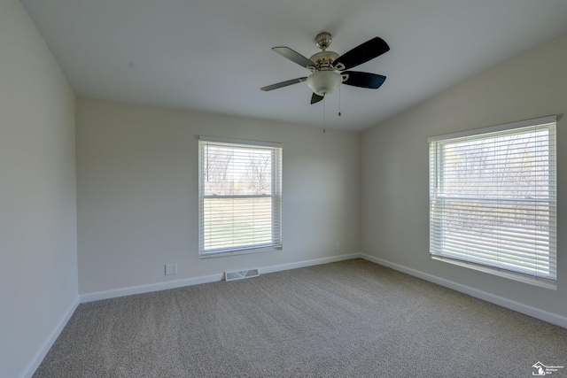 carpeted empty room featuring visible vents, a ceiling fan, vaulted ceiling, and baseboards