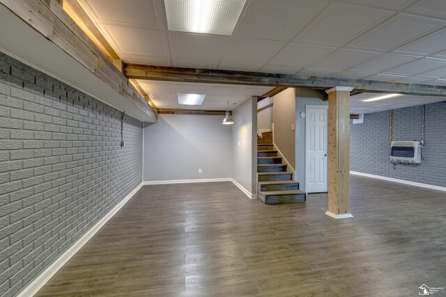 finished basement featuring baseboards, stairway, heating unit, and brick wall