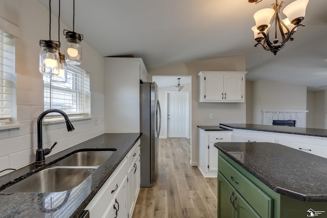 kitchen with a sink, light wood-type flooring, green cabinetry, white cabinets, and freestanding refrigerator