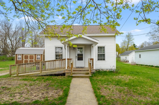 view of front of house with an outbuilding, a shed, a front lawn, and roof with shingles
