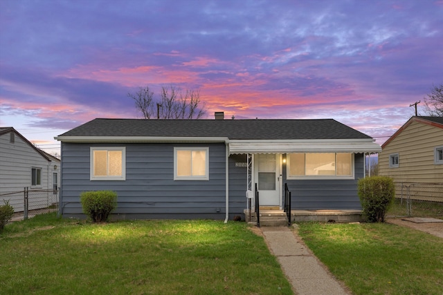 view of front of property featuring a shingled roof, fence, a yard, and entry steps