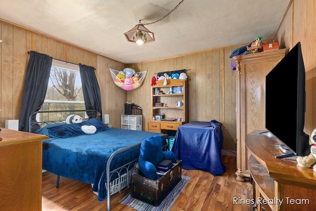 bedroom featuring wooden walls and wood finished floors