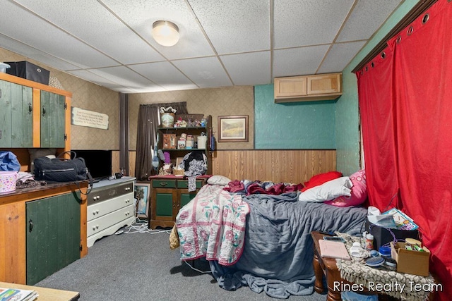 bedroom with a wainscoted wall, carpet, and a paneled ceiling