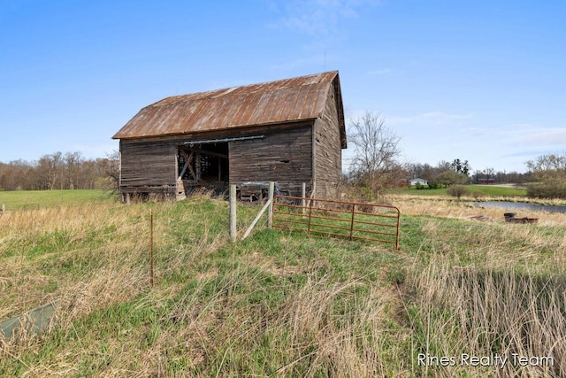 view of barn with fence and a rural view