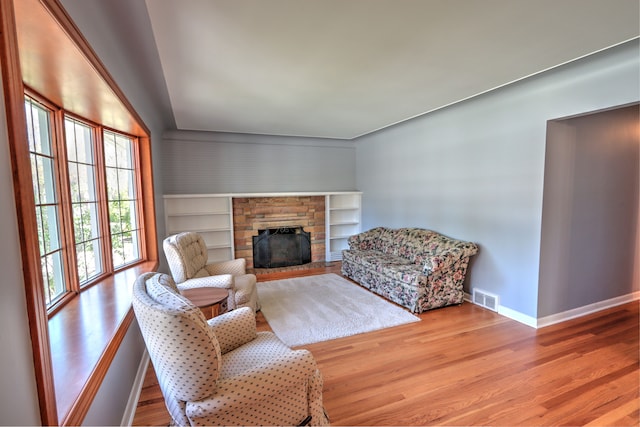 living room featuring visible vents, baseboards, wood finished floors, and a fireplace