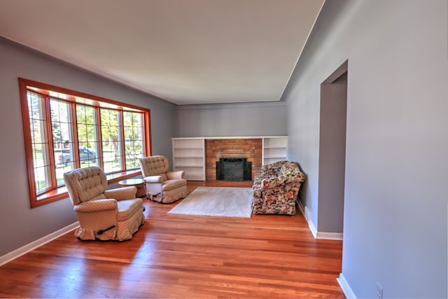 living area with baseboards, wood finished floors, and a fireplace
