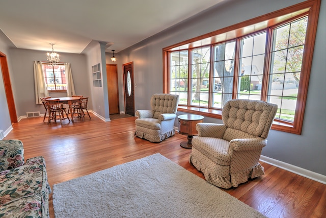 living room featuring baseboards, wood finished floors, a chandelier, and visible vents