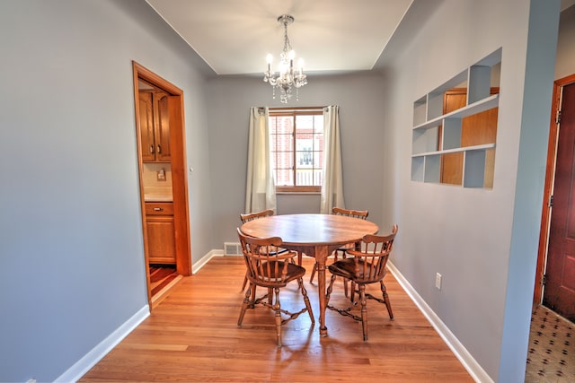 dining room featuring visible vents, light wood-style flooring, baseboards, and a notable chandelier