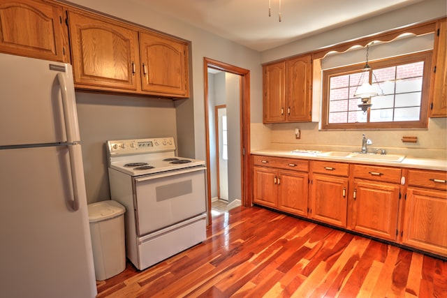 kitchen with white appliances, brown cabinets, a sink, and light countertops