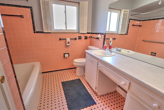 bathroom with a tub, tile walls, a wainscoted wall, vanity, and toilet